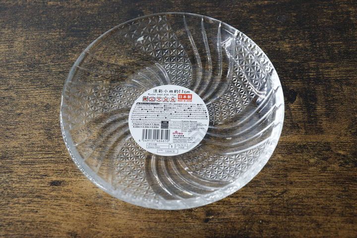 木目のテーブルに置かれたガラス小皿の裏面に商品情報シールが貼られている俯瞰写真