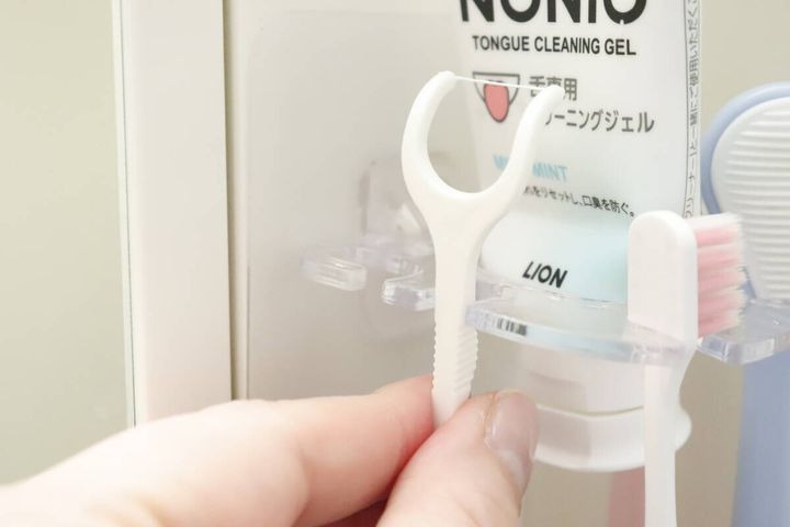 歯ブラシホルダーにY字フロスを引っ掛けている手元