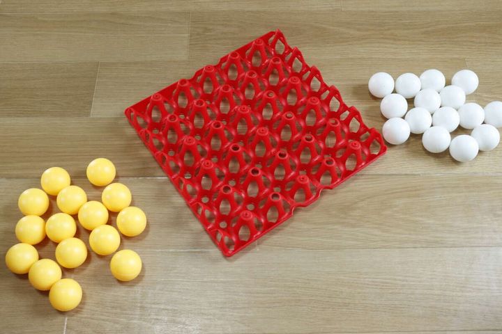 赤いボードと黄色・白色のピンポン玉が床に広げられている
