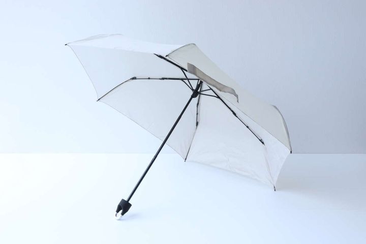 広げられたベージュの折りたたみ傘を斜め上から撮影