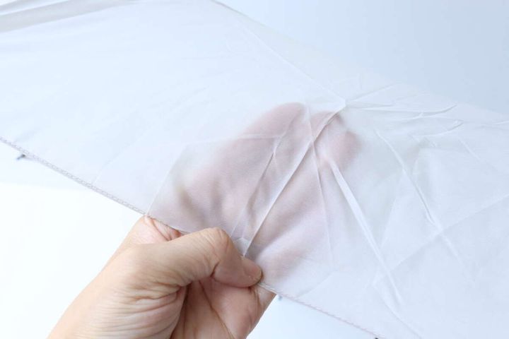 手が広げた傘の生地を指で透かして見せている様子