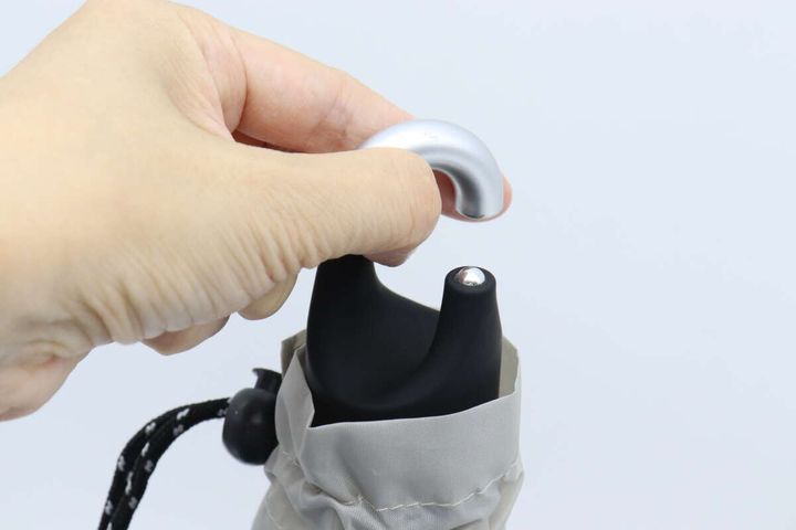 手が折りたたみ傘のカラビナ部分を掴んでいる様子