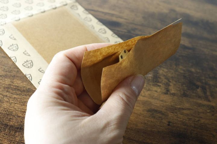 カメムシキャッチャーの粘着シートで折り紙のカメムシを完全に包み込み、封筒状に閉じている様子