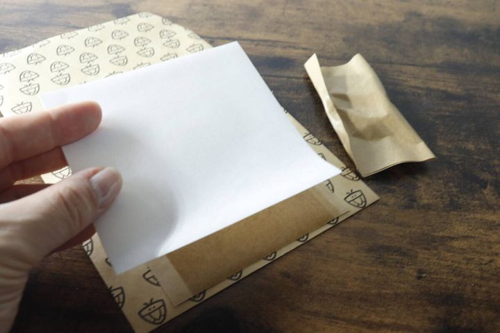 カメムシキャッチャーの粘着シートを保管するため、剥がした白い剥離紙を再度貼り付けている様子