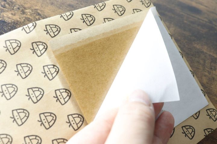 カメムシキャッチャーの粘着シートから、白い剥離紙を剥がしている様子