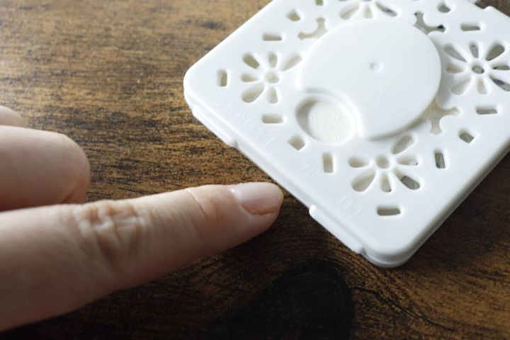 白いカメムシよけ芳香剤本体の側面を指で押して開けようとしている様子