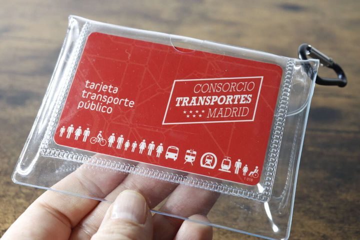 手が透明なポーチの背面ポケットに赤いカードを差し込んでいる様子