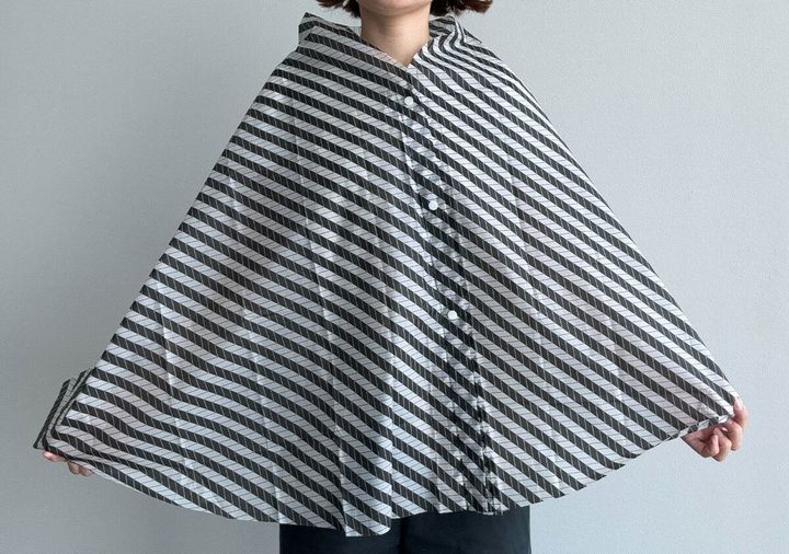 レインケープを羽織って広げた女性の全身