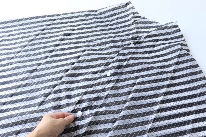 レインケープのスナップボタンを留める手元