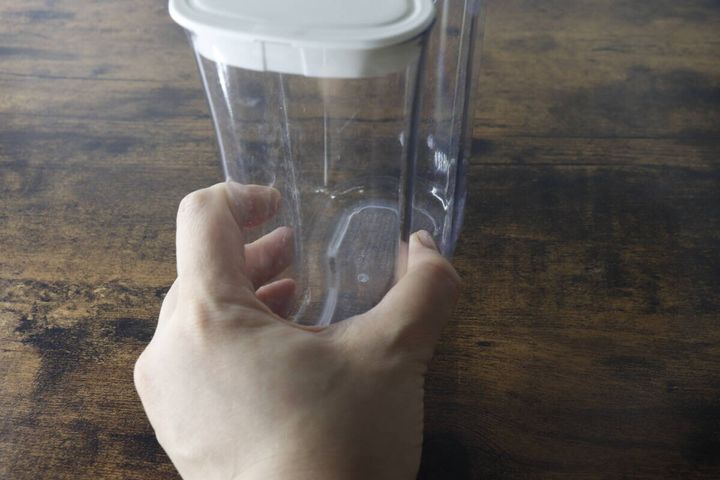 透明なピッチャーのくびれ部分を片手で持ち上げている