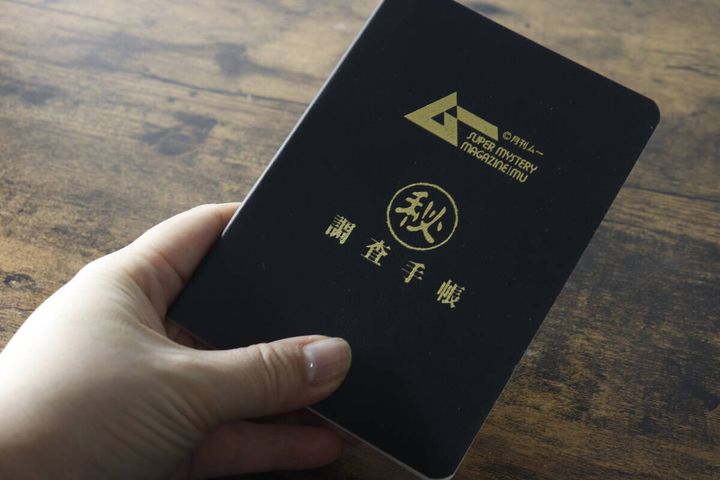 ムーのレザー調ノートを片手で持ち、サイズ感を示している手元の写真