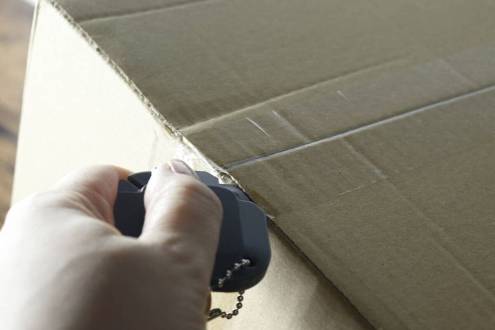 3WAY開封カッターで段ボールの梱包テープを切っている手元