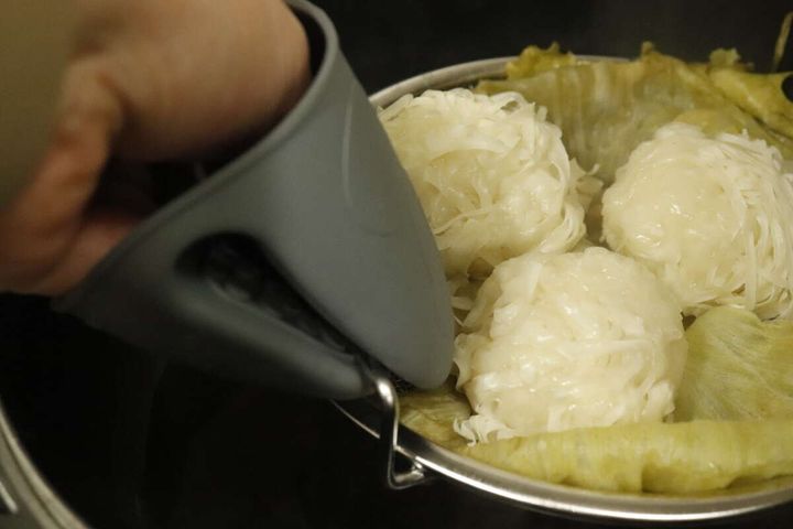 ミトンをはめた手がフライパンからメッシュザルを取り出す様子