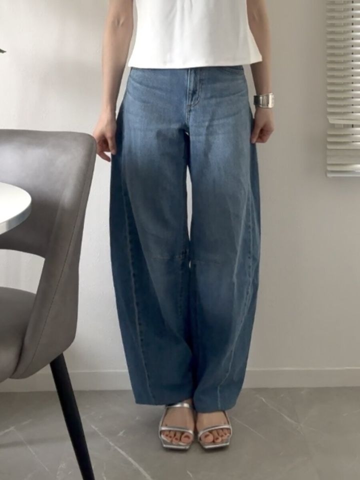 明るいブルーのバレルレッグジーンズを着用し立つ女性の全身