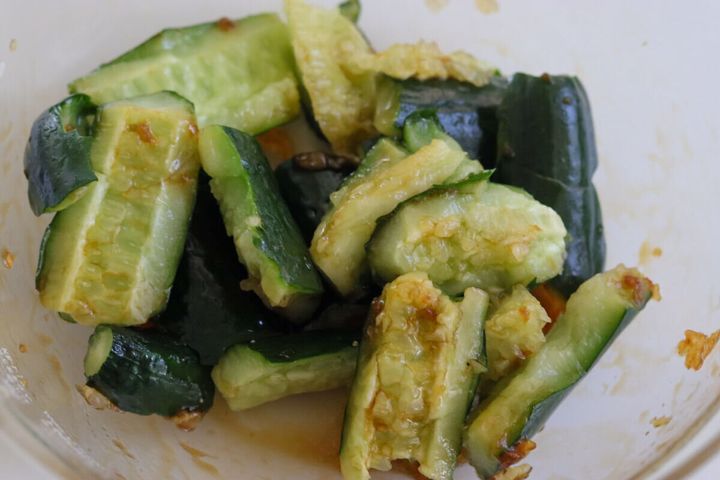 透明なボウルに、叩いたきゅうりと調味料のタレが混ぜ合わされている様子