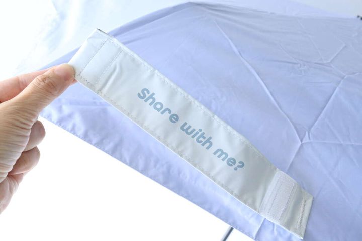 開いた傘の白い面ファスナーの留め具を指で示している