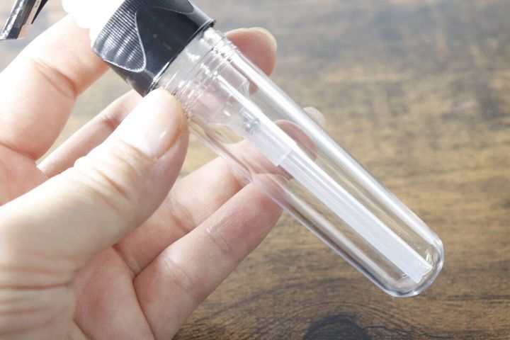 女性が透明なポンプボトルを手に持ちサイズ感を示している