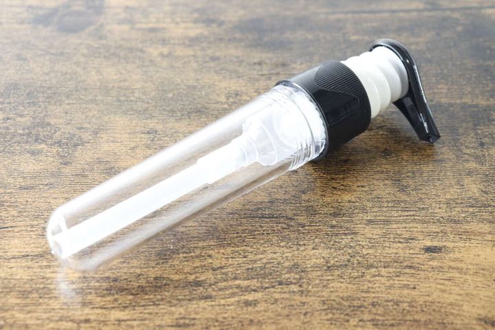 透明なポンプボトル本体を木目調のテーブルに置いた様子