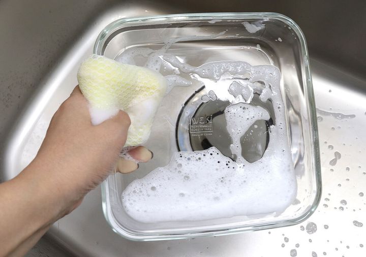 手が泡立てたスポンジでiwaki耐熱調理容器を洗っている様子