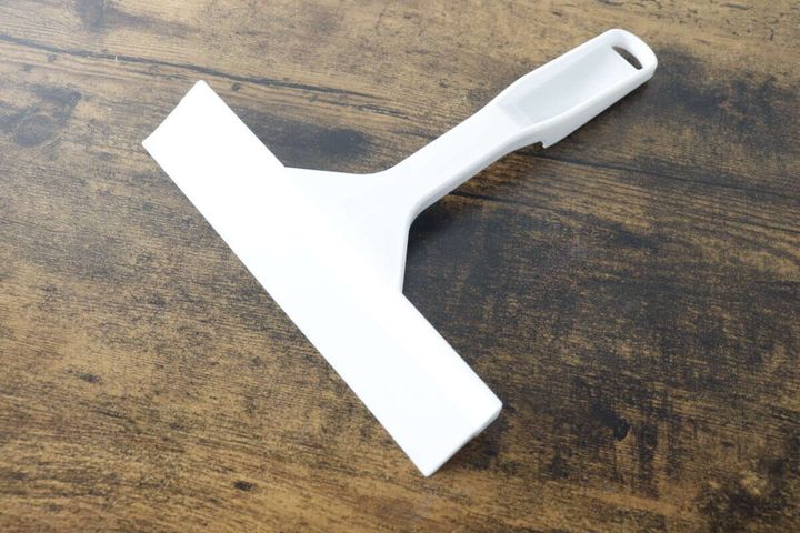 パッケージから出した白いダイソーの磁石でくっつく水切りワイパーが木目のテーブルに置かれている