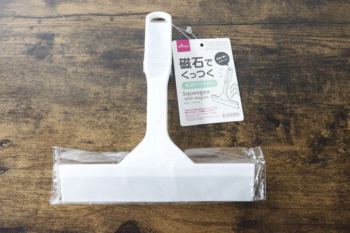 白いパッケージに入ったダイソーの磁石でくっつく水切りワイパーが木目のテーブルに置かれている