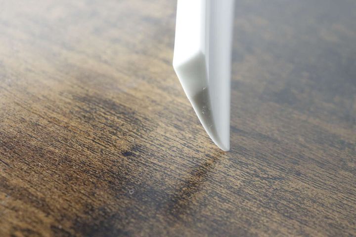 白い水切りワイパーのブレード先端部分が木目のテーブルに触れている様子をアップで捉えている