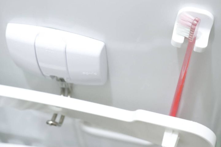 洗濯機横のラックに設置した歯ブラシキャッチに歯ブラシを掛けている様子