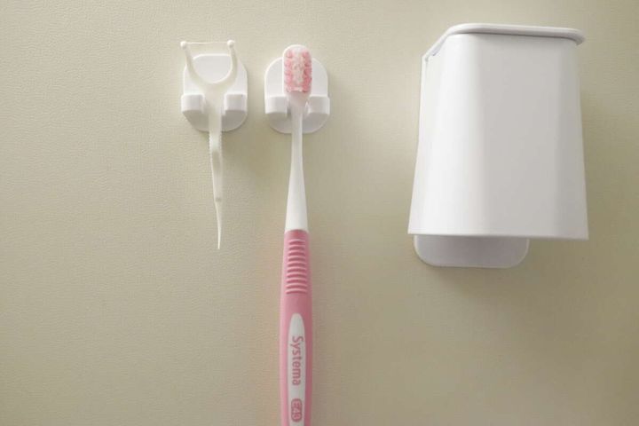 壁に設置された歯ブラシキャッチに歯ブラシとY字フロスを収納