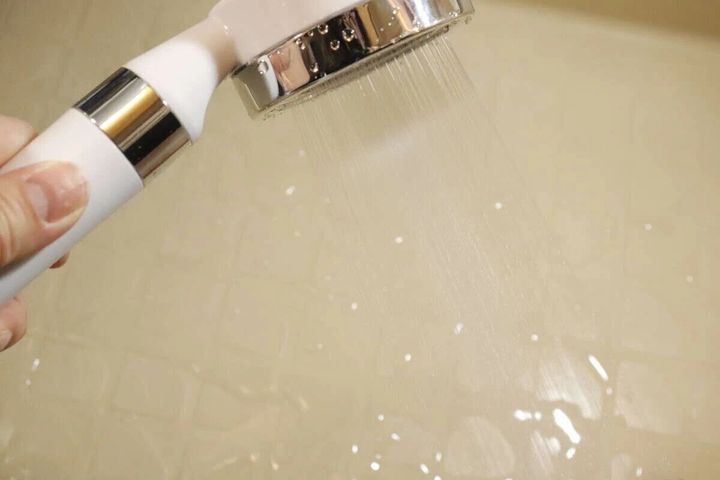 手で持ったシャワーヘッドから細かな水が勢いよく出ている