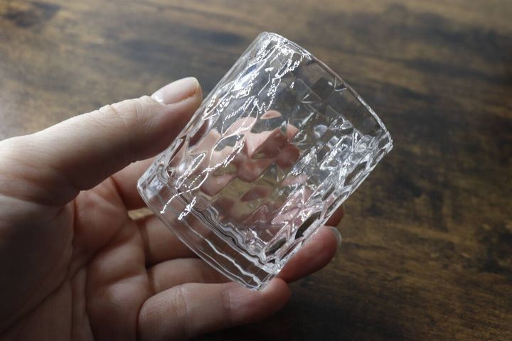 ダイヤモンドのような模様が特徴のミニグラスを片手で持っている様子