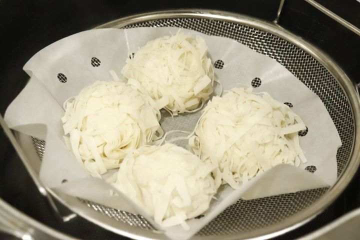 フライパンにセットされた浅型ザルで焼売のようなものを蒸している様子