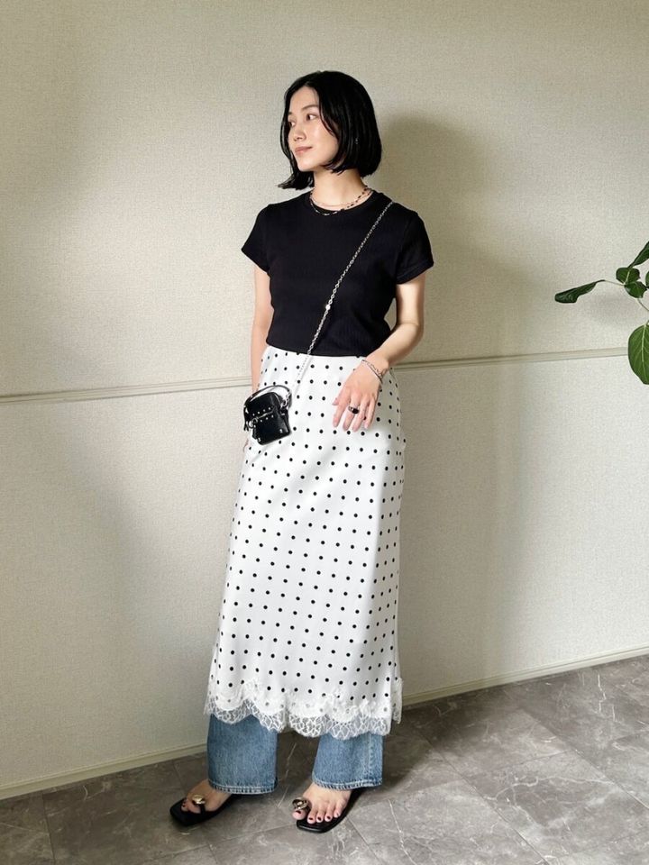 黒Tシャツにドット柄レーススカートとデニムを重ね着した女性