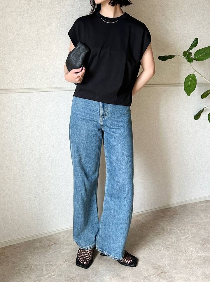 黒いTシャツとデニムのシンプルなNGコーデで、女性がバッグを持っている