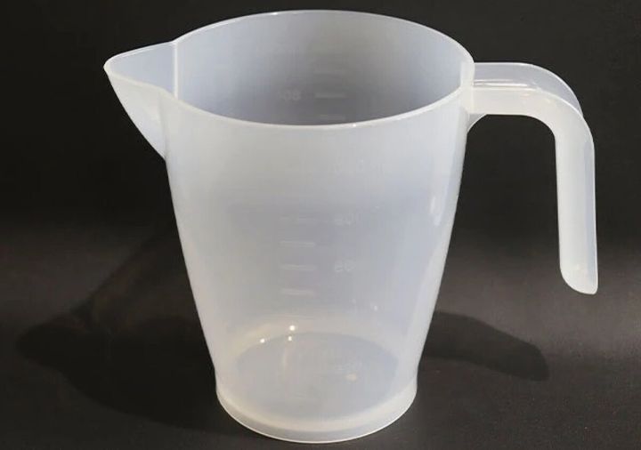 透明なプラスチック製の万能メジャーカップが黒い背景に置かれている