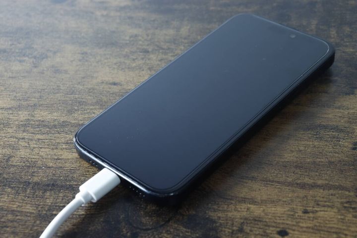 黒いスマートフォンに白いType-C充電ケーブルを接続している