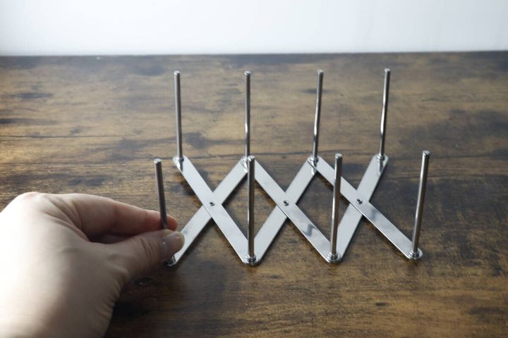 女性の手がダイソー伸縮ステンレス皿立てを少し広げている様子