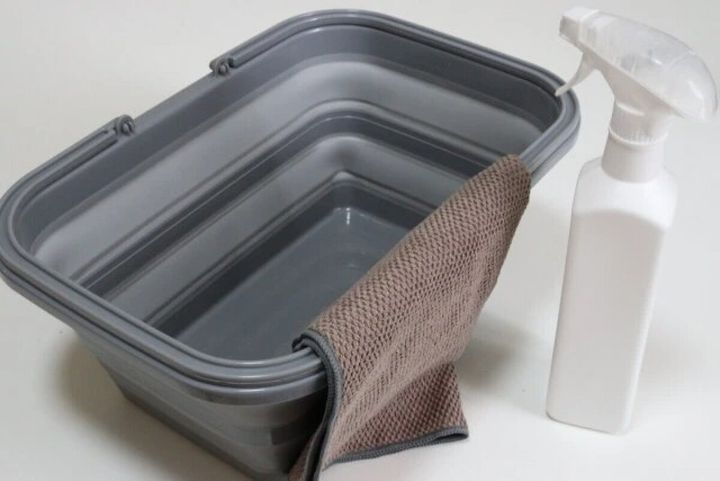 グレーの折りたたみバスケットとスプレーボトル、タオル
