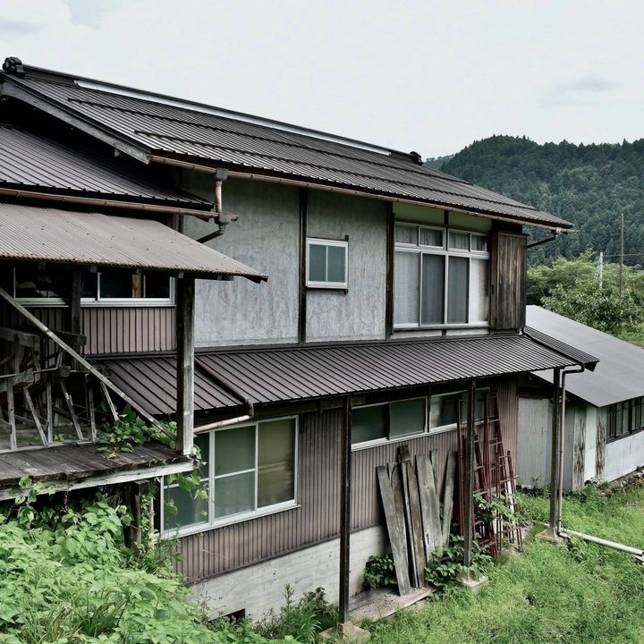 草の伸びた庭先に建つ、古い木造の家