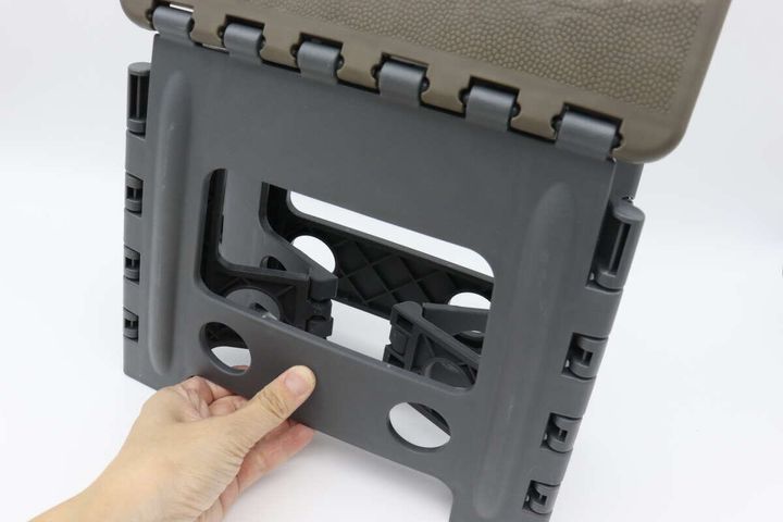 折りたたみイスの脚をたたむ動作をしている手元