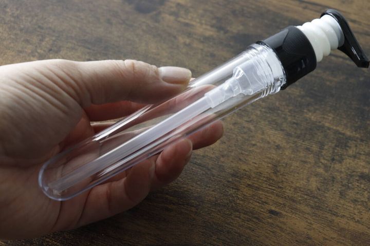 女性の手が透明なポンプボトルを握っている様子