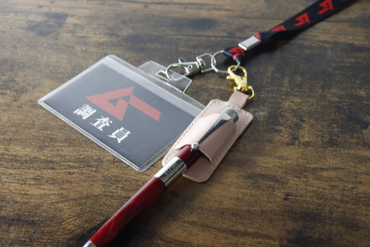 赤いペンを差したペンホルダーをIDケースに付けている