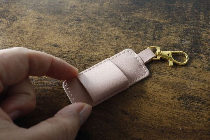 女性の指がピンクのペンホルダーのベルト部分を押している