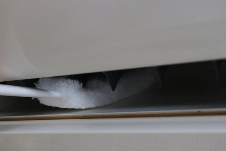 エアコンの送風口の狭い隙間を、白いクリーナーで掃除している