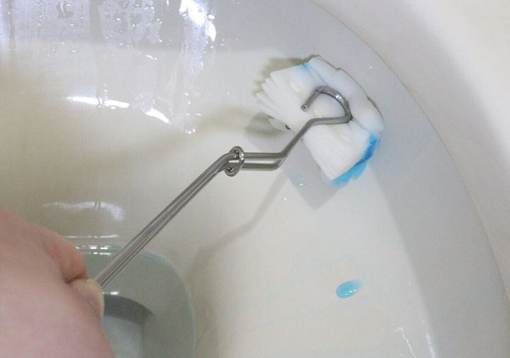 手がステンレス製トイレブラシで便器内をゴシゴシ掃除している