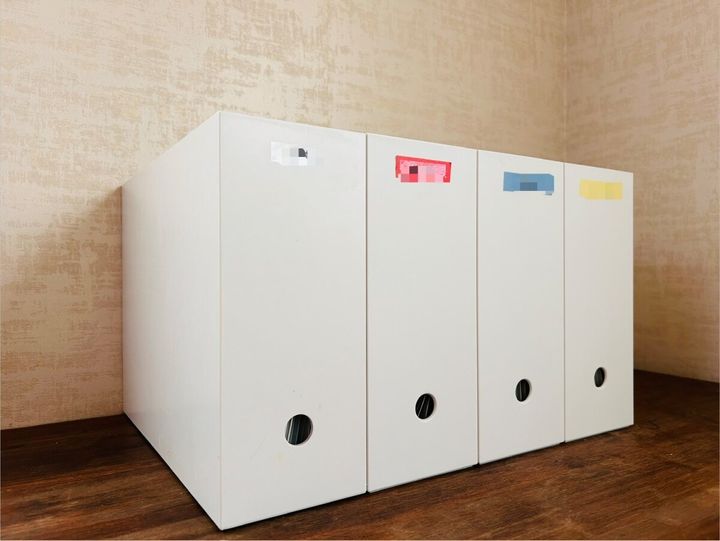 色分けされたラベルが貼られた白いファイルボックスが4つ並ぶ