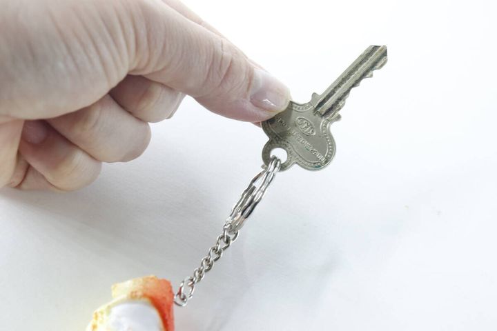 女性の指がカニ爪キーホルダーのリングに鍵を取り付けている様子