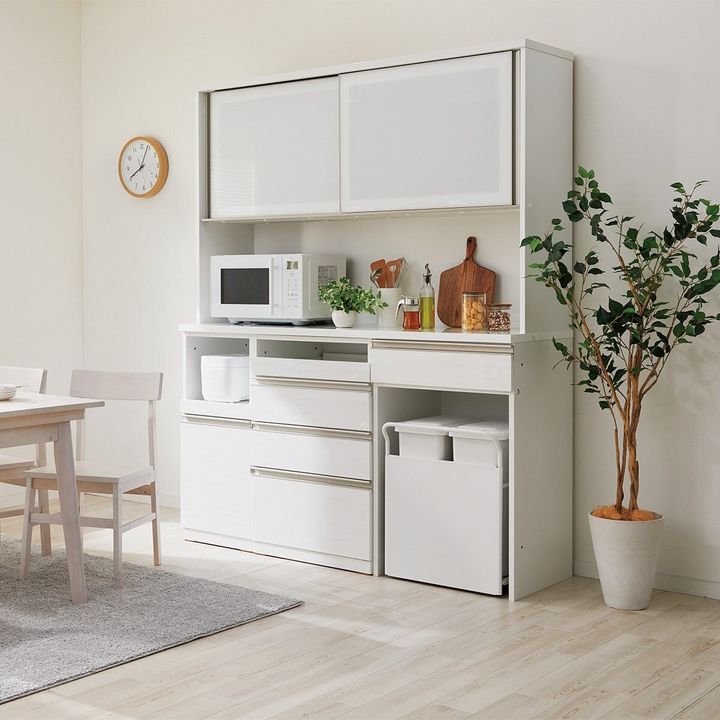 白い壁の部屋に置かれた、白を基調とした組み合わせキッチンボードとダイニングセット