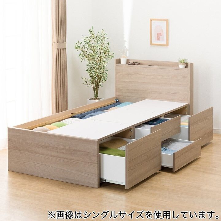木目調のチェストベッドフレーム。引き出しが複数開いており、収納されている衣類が見える