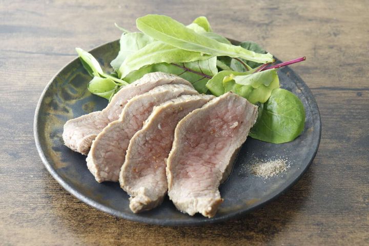 スライスされた肉とサラダが盛られた皿の横に燻製塩こしょうが添えられている