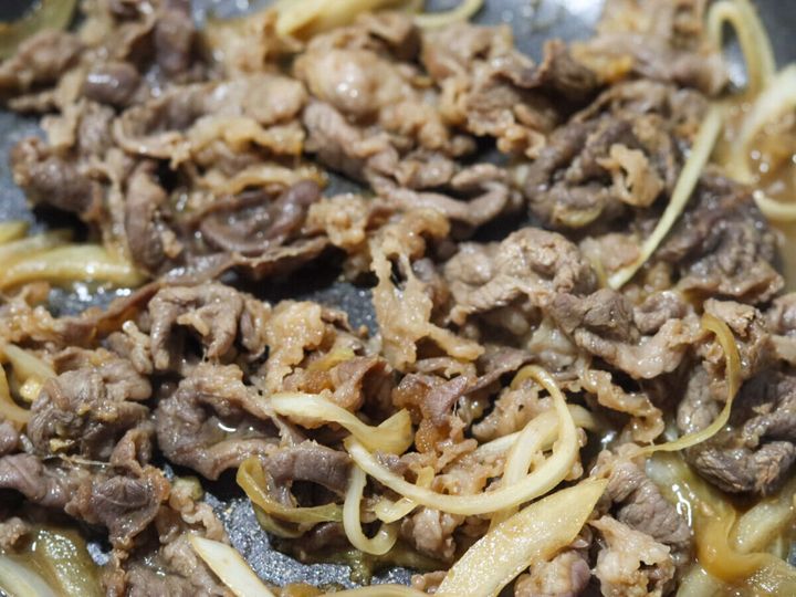 フライパンで牛肉と玉ねぎが炒められ、火が通り茶色く煮詰まっている様子